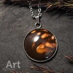 Een handgemaakt, glanzend bruine hanger met warme amber- en roomwervels aan een zilveren ketting, liefdevol op steen gelegd.